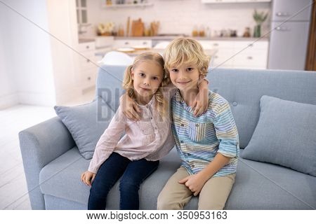 Two Blod Kids Sitting Next To Each Other And Hugging