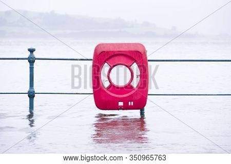 Sea Flood Onto Street With Red Life Safety Ring During Bead Extreme Rain And Weather Storm In Uk