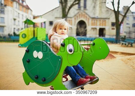 Adorable Toddler Girl Having Fun On Spring Rider On Playground. Outdoor Activities For Kids