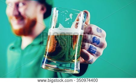 Portrait Of Excited Man Holding Glass Of Beer On St Patricks Day Isolated On Green