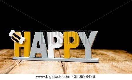 Happy - Joyful Sign With Bee Isolated On Dark Wooden Background