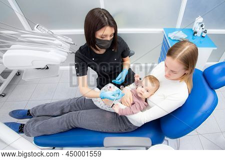 Mom And Baby At The Reception At The Pediatric Dentist. First Visit To The Dentist. Diagnosis And Tr
