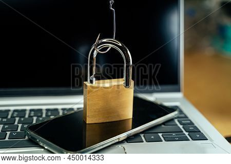 Fishhook Opening A Padlock Over A Laptop