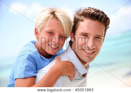 Daddy giver piggyback ride til søn ved stranden