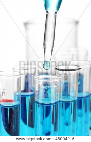Labor-Pipette mit Tropfen Farbe Flüssigkeit über Glas Reagenzgläser, Nahaufnahme, isolated on white