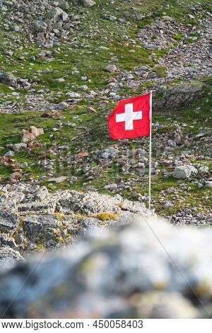 Sustenpass, Switzerland - August 13, 2021: Red Swiss National Flag In The Natural Ambient Of Sustenp