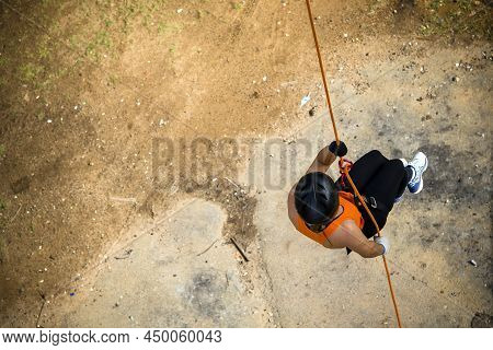 Woman Practicing Rappel On A Pedestrian Walkway.