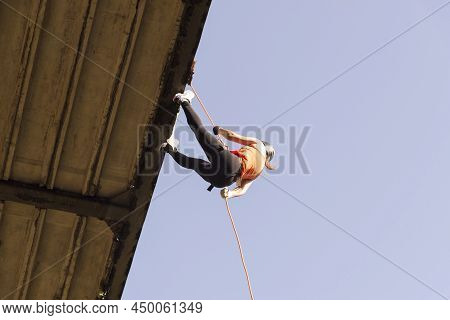 Woman Practicing Rappel On A Pedestrian Walkway.