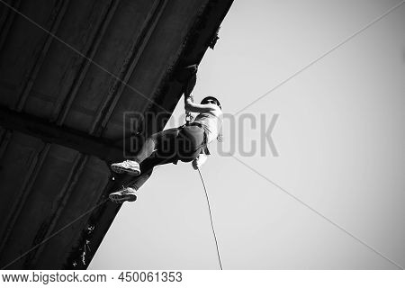 Woman Practicing Rappel On A Pedestrian Walkway.
