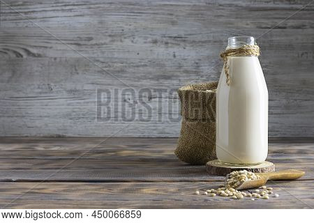 Barley Milk On A Glass Bottle On A Wooden Table. Barley Grains In A Canvas Bag In The Background. Gr