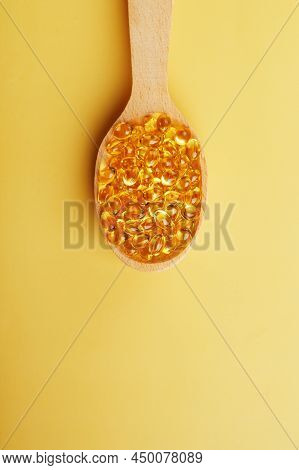 Vitamin D3 In A Wooden Spoon On A Bright Yellow Background