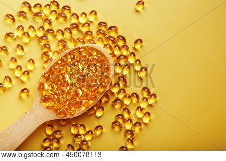 Vitamin D3 In A Wooden Spoon On A Bright Yellow Background