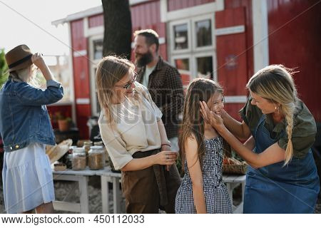 Happy Girl With Her Mother Meeting Her Aunt At Local Family Farmers Market.