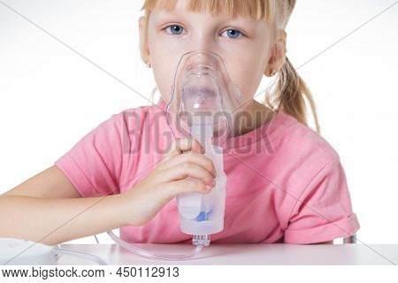 A Little Girl 5 Years Old In A Pink T-shirt Breathes Into A Nebulizer For Lung Disease. Treatment Of