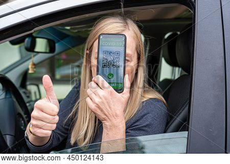 Driver In Car Shows A Digital Covid-19 Immunity Vaccine Passport, New Normal Travel Concept