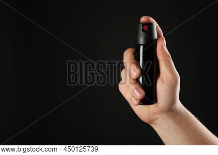 Man Holding Pepper Spray On Black Background, Closeup. Space For Text