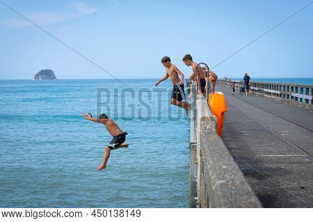 Tolaga Bay New Zealand - February 5 2022; Local Boys Jumping Of Tolaga Bay Wharf Under Encouragement