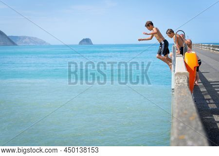 Tolaga Bay New Zealand - February 5 2022; Local Boys Jumping Of Tolaga Bay Wharf Under Encouragement