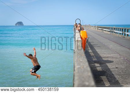 Tolaga Bay New Zealand - February 5 2022; Local Boys Jumping Of Tolaga Bay Wharf Under Encouragement