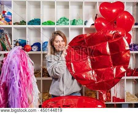 Woman Holds In Her Hands A Large Unblown Red Ball Of Foil In The Shape Of Heart.
