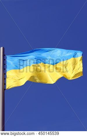 Yellow-blue National Flag Of Ukraine Flutters Against The Blue Sky Close-up