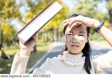 Asian Child Girl Walking Outdoor Protects From The Sunlight Uv Rays With Her Book,female Teenager Wo