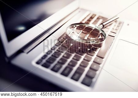 Magnifying glass on laptop keyboard searc for online documents background