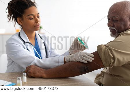 Senior Patient Getting Vaccinated Sitting In Medical Center