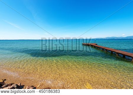 Panoramic View Of Lake Garda (lago Di Garda) And Small Wooden Pier Near The Small Villages Of Lazise