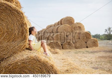 Relaxed Young Girl Seating On High Haystack Wearing Sundress Leaning On Another Hayrick With Closed 