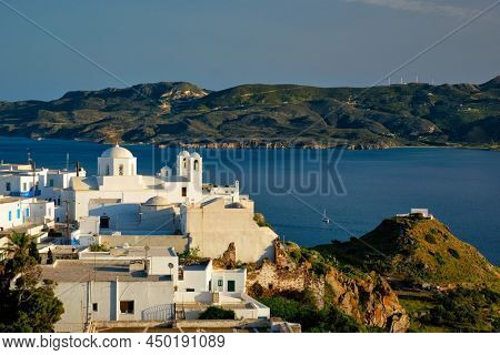 View of Plaka village on Milos island with traditional greek white houses with Greek Orthodox christian churck on sunset. Plaka town, Milos island, Greece