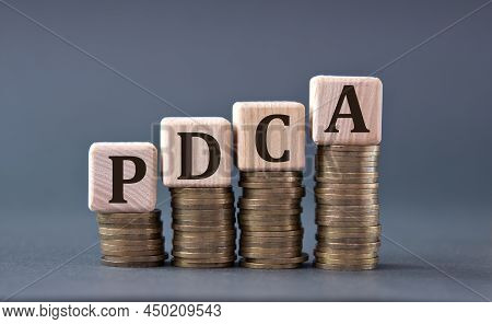 Pdca (plan-do-check-act) - Acronym On Wooden Cubes On Coins On A Gray Background. Business Concept