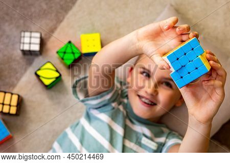 Top View Happy Male Kid Assembling Multicolored Mind Logical Toy Rubiks Cube With Positive Emotion