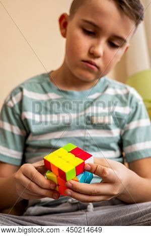 Focused Male Teenager Assembling Multicolored Pieces Of Rubiks Cube Enjoying Mind Development