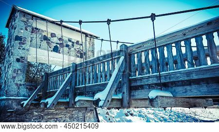 A Snow Covered Hiking Trail Bridge Over A Frozen River At A Local Park.