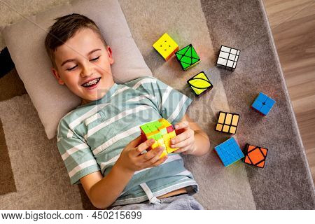 Top View Happy Male Kid Assembling Multicolored Mind Logical Toy Rubiks Cube With Positive Emotion
