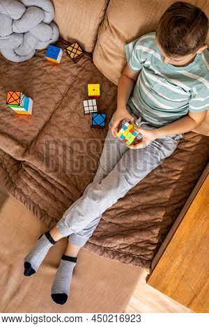 Top View Male Kid Assembling Multicolored Rubiks Cube 4x4 Relaxing Sitting On Couch