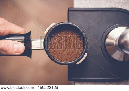 Barista Tampering Coffee In Portafilter Using Tamper. Close-up Fresh Coffee Preparation Process