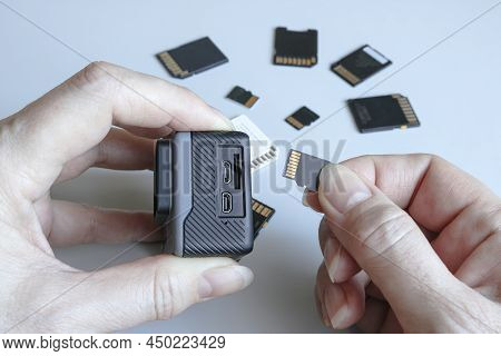 Action Camera And Microsd Memory Card In Hands On The Back Of Other Sd Memory Cards. Background From