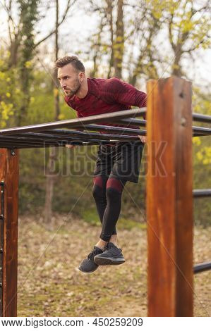 Athletic Man Doing Pullups While Doing Morning Training Session In A Street Workout Park