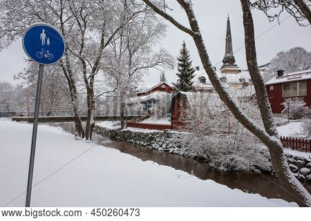 Idyllic nordic cityscape Vasteras old town in snow Traffic sign for cyclists and pedestrians Swedish traditional red houses, pointed spire cathedral Svartan river Scandinavia, White winter in Sweden