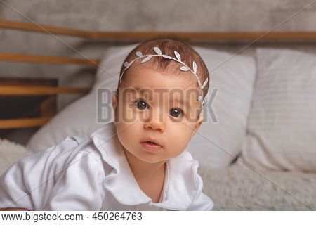 Little Baby Girl In White Bodysuit And Headband Standing On All Fours. Looking To The Camera. Baby S