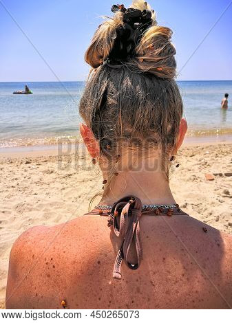 On The Back And Hair Of A Woman Relaxing On The Beach In A Bikini, A Large Cluster Of Ladybug Insect