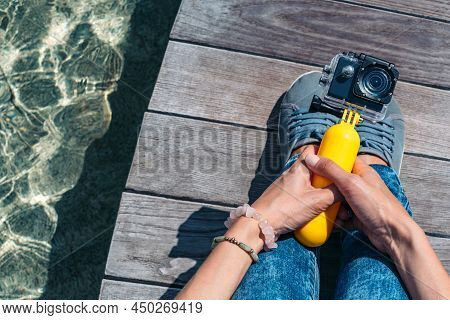 Action Camera In The Hands Of A Girl. Against The Backdrop Of A Wooden Deck, A Tabletop On The Surfa