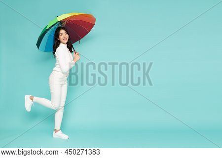 Young Asian Woman Holding Rainbow Umbella Standing Isolated On Green Background, Full Body