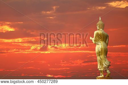 Gorgeous Golden Buddha Image In Waking Posture On Golden Red Sky With Crepuscular Rays Background