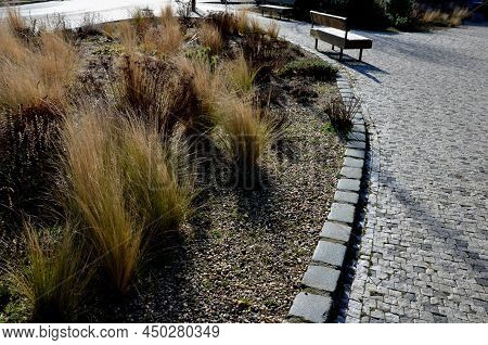 Perennial Bed Mulched With Gray Gravel In Front Of A Limestone Stone Wall In A Square With Benches W