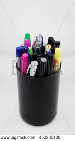 different varieties of gel, ball and colorful pens in a black pen holder isolated in a white backgro