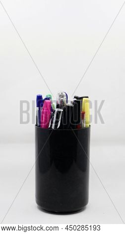 Different Varieties Of Gel, Ball And Colorful Pens In A Black Pen Holder Isolated In A White Backgro