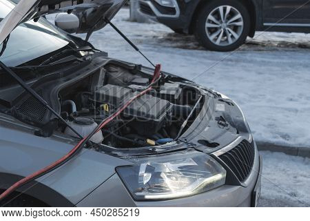 Charging A Car Battery In Winter. Help On The Road. Close-up. Connecting High Voltage Wires To The C